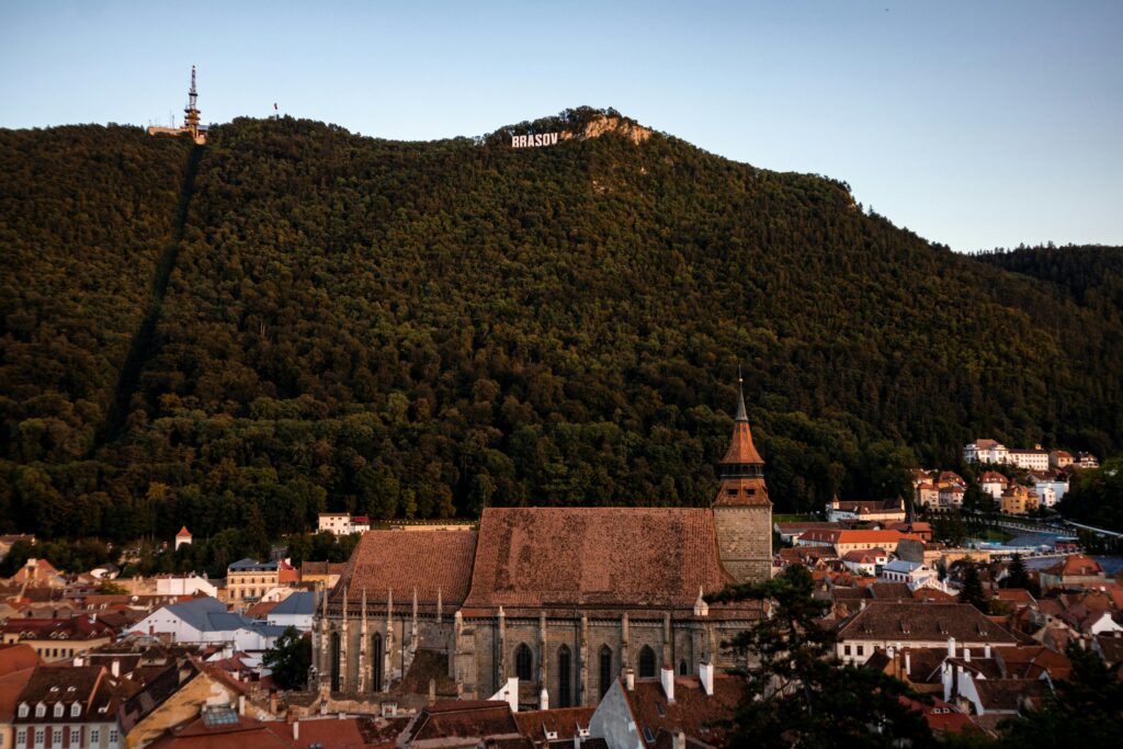 A stunning aerial view of Braşov's historic downtown and Mount Tâmpa at sunset.