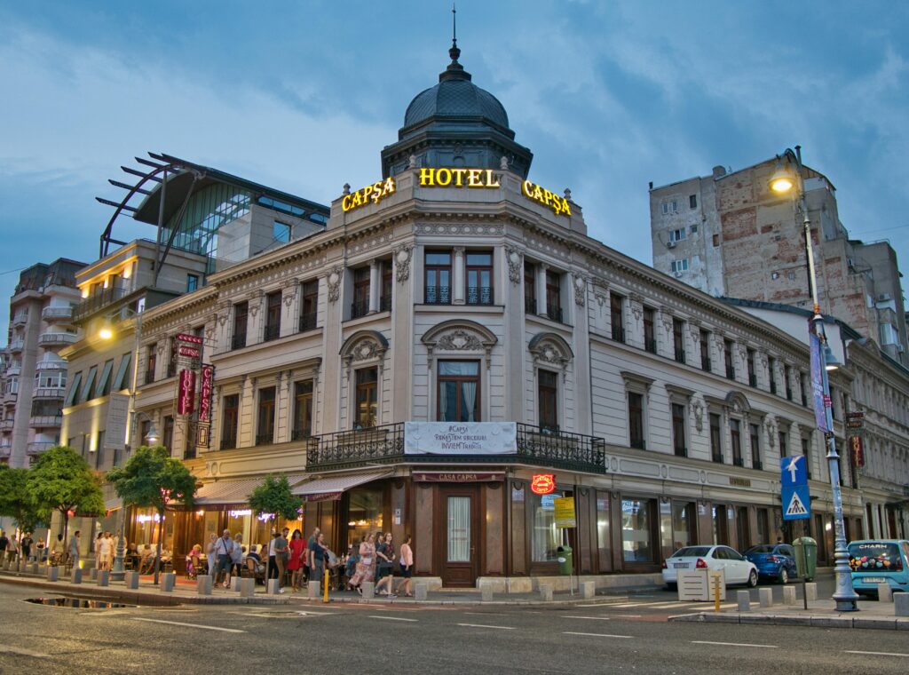 Charming view of Hotel Capsa, an architectural landmark in central Bucharest, bustling with evening life.