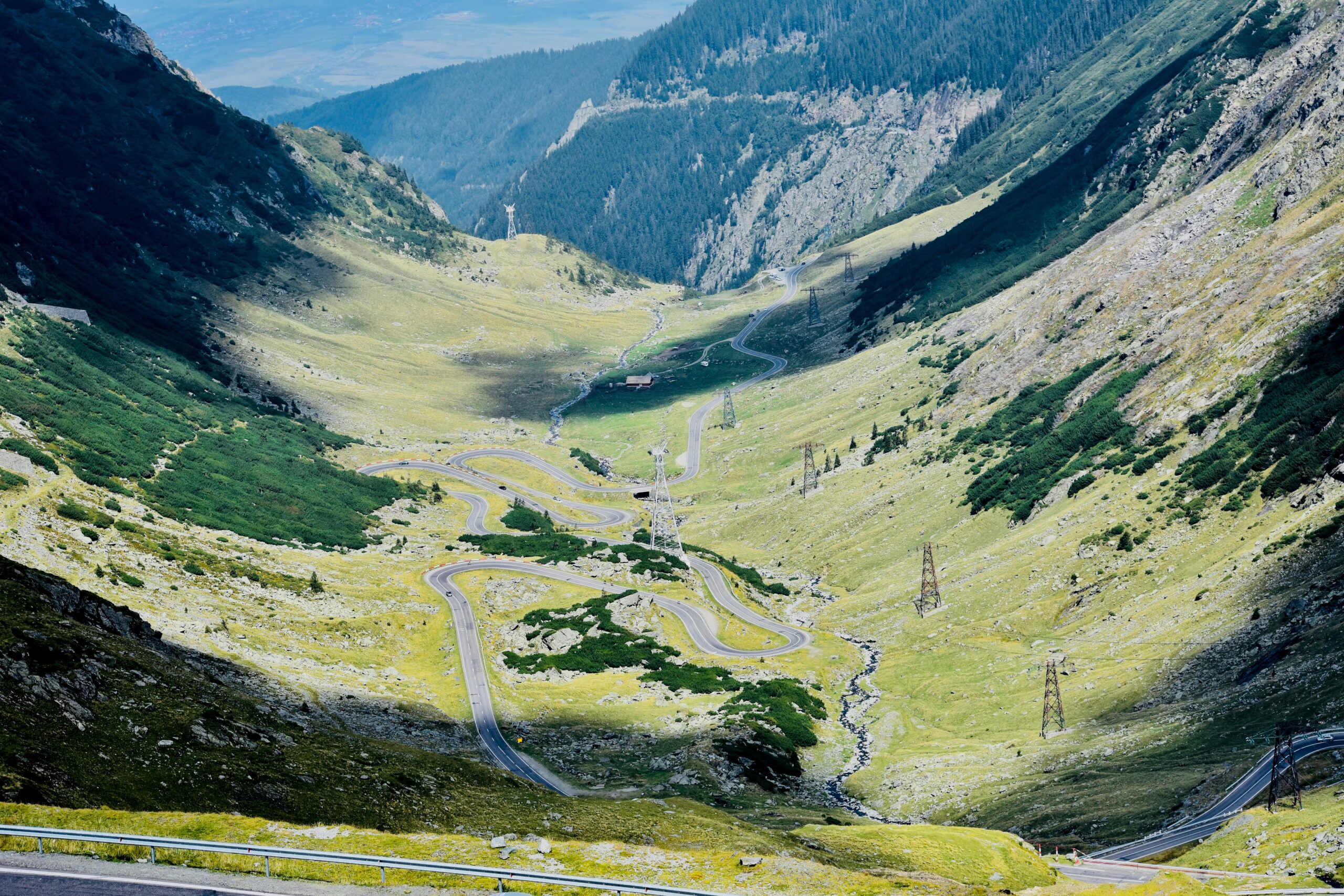 A winding road through lush valleys and rugged mountains in Buda, Romania. Perfect for nature lovers.