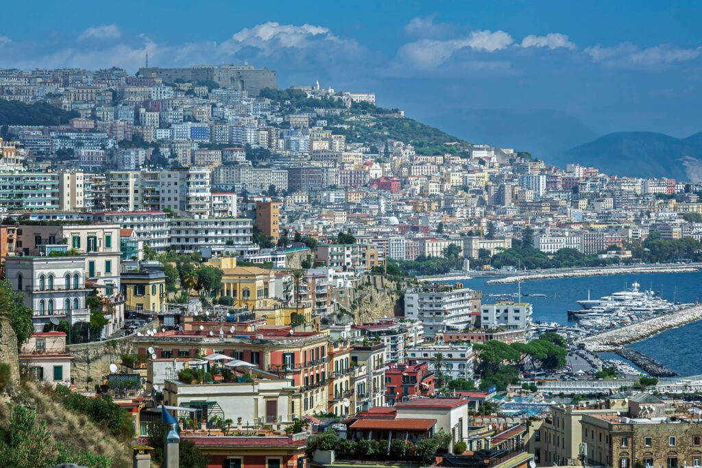 A breathtaking view of the colorful buildings and coastline of Naples, Italy, showcasing the vibrant city life and stunning sea.