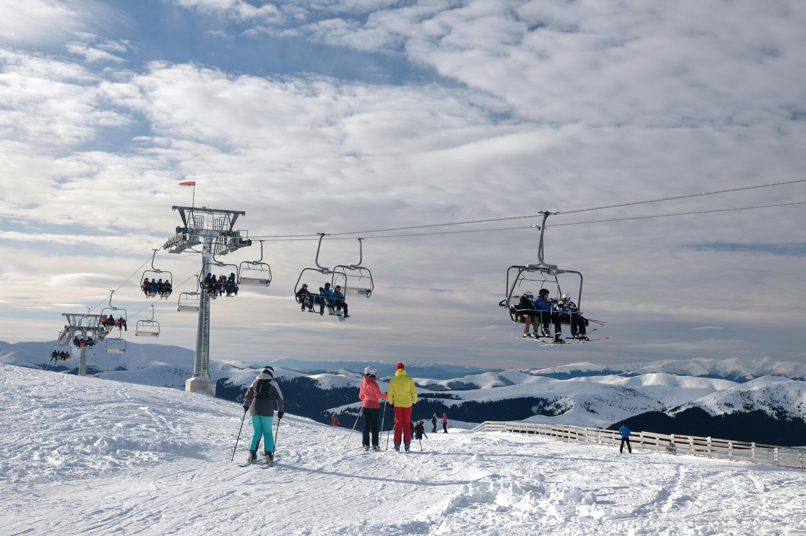 A scenic view of skiers and ski lifts on snowy mountains in Sinaia, Romania.